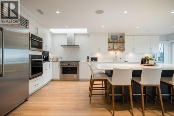 Spacious white kitchen with stainless steel appliances, dual ovens, and a central island. - 1584 Beach Grove Road, Delta