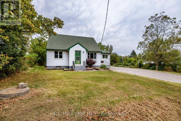 Front view of a white house with a green roof and green trim. - 1585 Townline Road N, Clarington