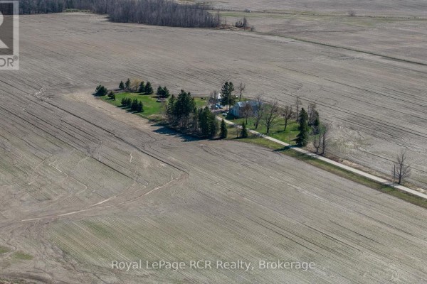 Aerial view of a farmhouse and trees surrounded by cleared agricultural fields. - 158567 Highway 10, Melancthon