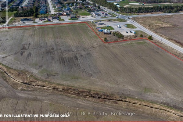 Aerial view of a property boundary marked in red, encompassing agricultural fields adjacent to a residential area and highway. - 158567 Highway 10, Melancthon