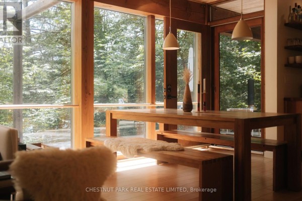 Dining area with wooden table and benches, large windows with forest view, and wood paneled ceiling. - 158a Ponacka Road, Hastings Highlands