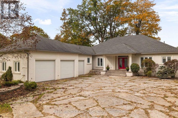 Side view of a white stucco house with a three-car garage and a stone driveway. - 159 Creighton Street, Ramara