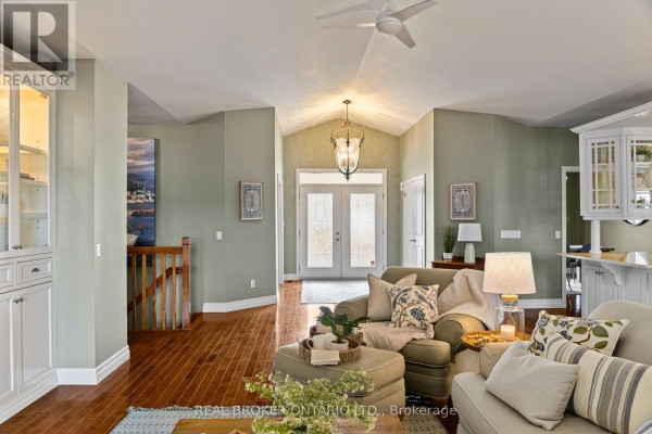 Living room with green walls, hardwood floors, and vaulted ceilings with a chandelier. - 159 Creighton Street, Ramara
