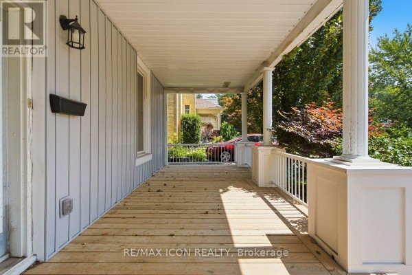 View from the covered front porch showing the wooden floorboards and railing. - 159 Front Street W, Strathroy Caradoc