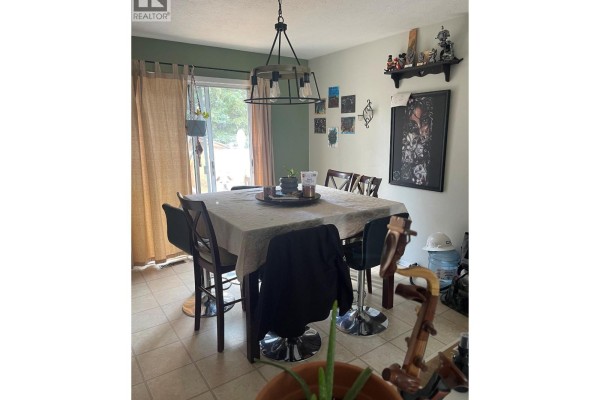 Dining room with a table set for multiple people, tile flooring, and patio doors leading outside. - 159 Gwillim Crescent, Tumbler Ridge