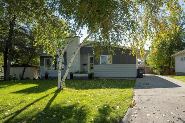 Side view of a grey and dark grey sided bungalow with a paved driveway and trees. - 159 Larchdale Crescent, Winnipeg