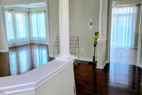 Interior hallway with polished hardwood floors, white pillars, and doorways leading to rooms with white curtains. - 159 Riding Mountain Drive, Richmond Hill