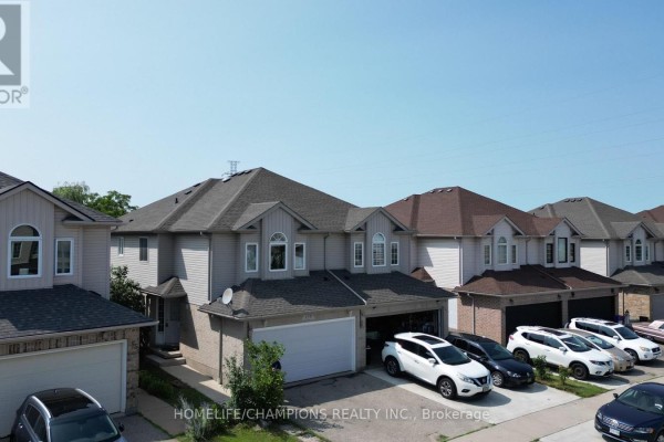 Aerial view of multiple townhouses with cars parked in driveways under a clear sky. - 159 Snowdrop Crescent, Kitchener