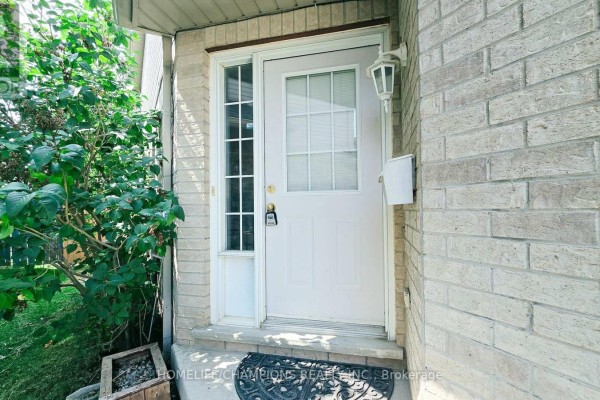 Close-up of a white front door with a glass insert, sidelight, and brick exterior. - 159 Snowdrop Crescent, Kitchener