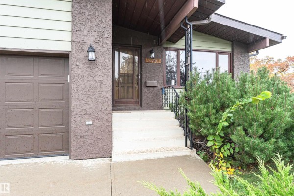 Close-up of the house entrance with a brown door and concrete steps. - 15903 111 St Nw, Edmonton