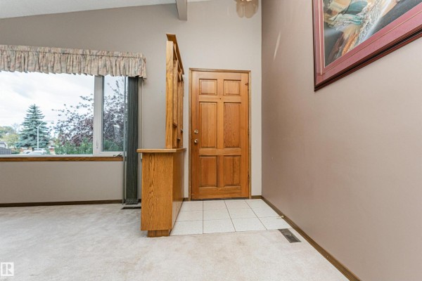 Interior view of the front entrance with a wooden door, built-in cabinet, and large window. - 15903 111 St Nw, Edmonton