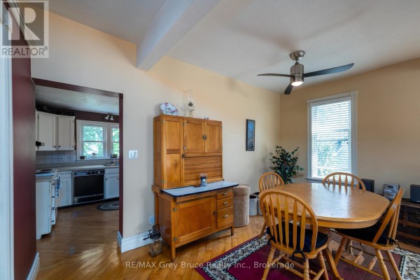 Dining area with a wooden table, hutch, and view into the kitchen area. - 1591 5th Avenue W, Owen Sound