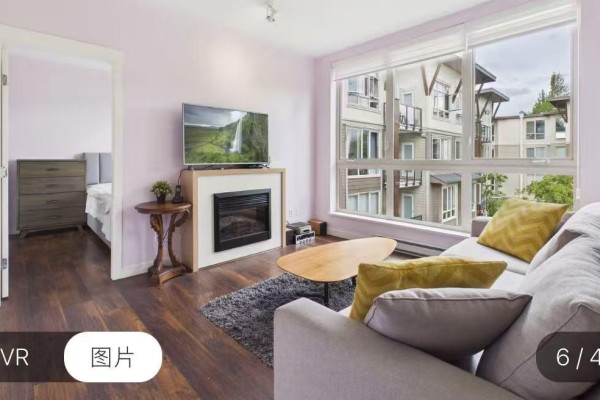 Living room with a fireplace, mounted television, sofa, and a view of the building exterior and trees. - 15918 26 Avenue, Surrey
