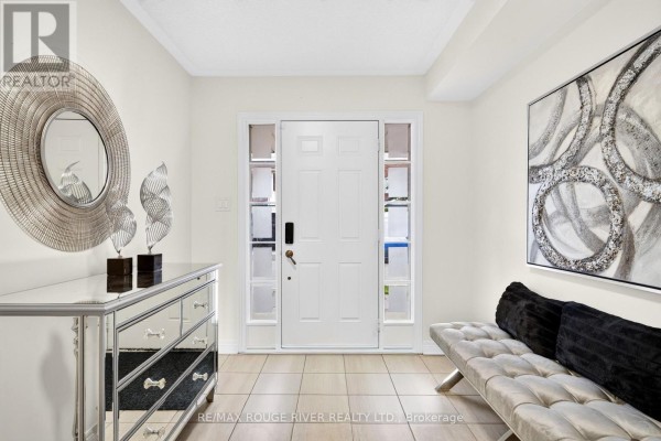 Tiled foyer with a white front door, mirrored dresser, bench, and abstract wall art. - 1594 Brandy Court, Pickering