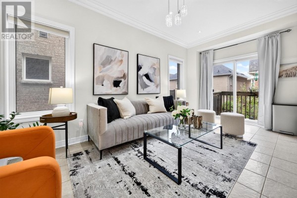 Living room with a grey tufted sofa, glass coffee table, orange chairs, and patio doors. - 1594 Brandy Court, Pickering