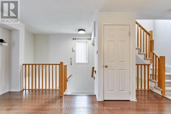 Interior hallway with hardwood floors, white doors, and wooden railings. - 15951 Bayview Avenue, Aurora