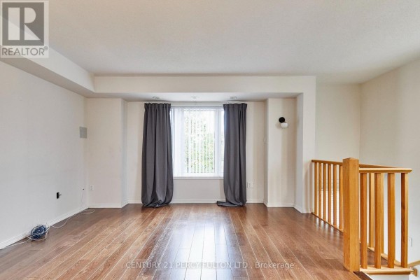 Spacious living area with hardwood floors and dark grey curtains on window. - 15951 Bayview Avenue, Aurora