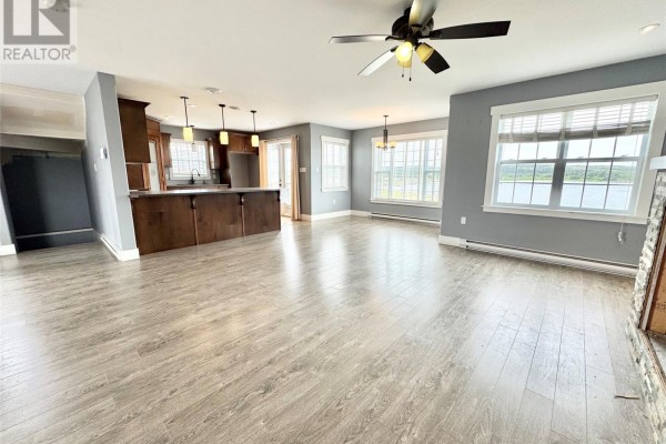 Open concept living and kitchen area with grey walls, light wood floors, dark wood cabinets, and water views. - 15a Main Street, Tilting