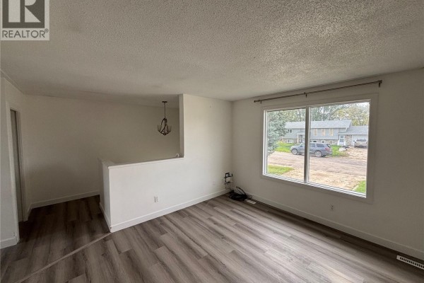 Living room with a large window and a half wall separating it from a staircase. - 15b Erixon Place, Clavet