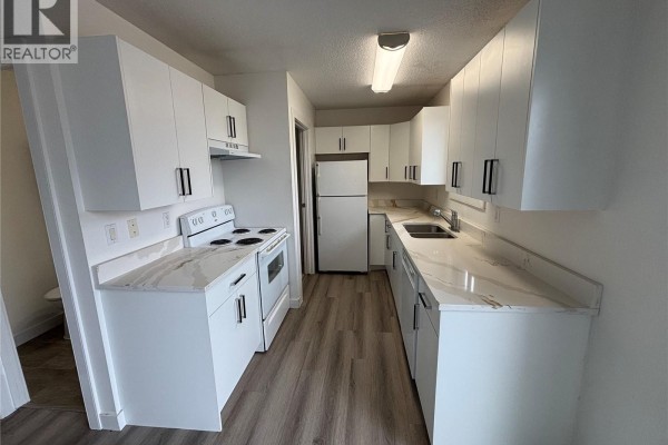Kitchen with white cabinets, white countertops, white appliances, and wood-look flooring. - 15b Erixon Place, Clavet
