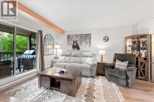 Living room with sofa, recliner, coffee table, and balcony access featuring an outdoor grill. - 15c 3102 Panorama Ridge, Whistler