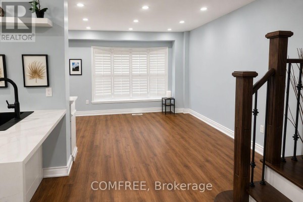 Close-up exterior view of a brick townhouse with a stone entryway and garage doors. - 15d View Green Crescent, Toronto