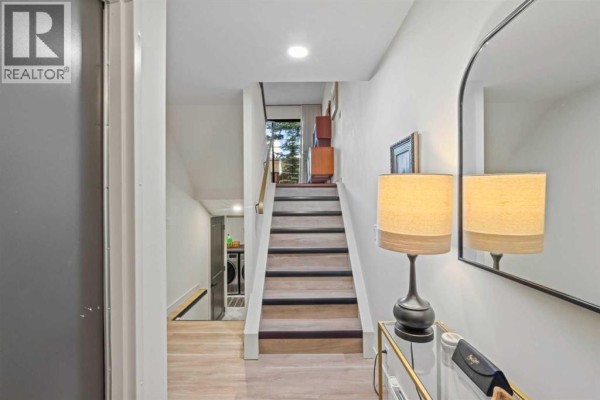 Hallway with stairs leading up and a view of the laundry room below. - 16, 140 Point Drive Nw, Calgary