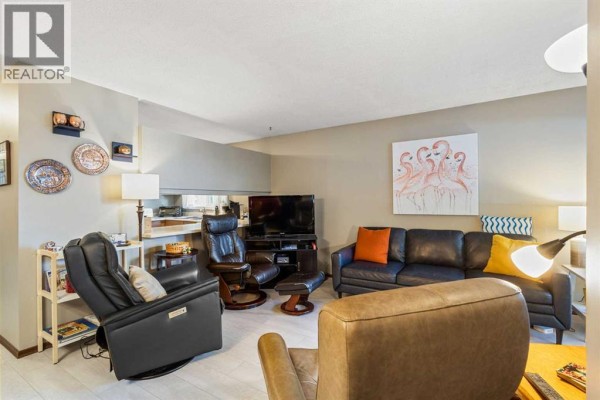 Living room with leather furniture, television, and sliding glass door. - 16, 3015 51 Street Sw, Calgary