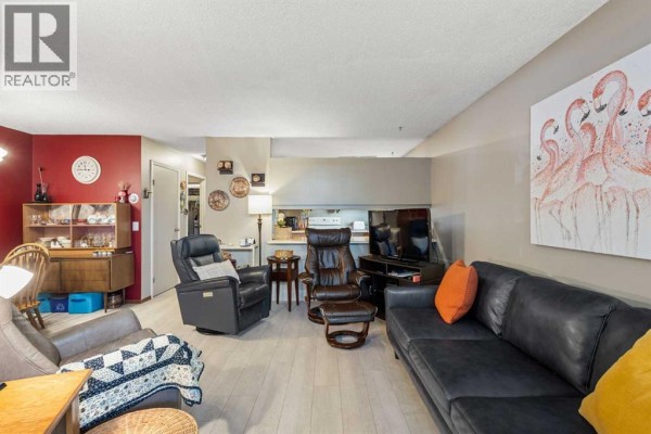 Living room with leather furniture, television, and a red accent wall. - 16, 3015 51 Street Sw, Calgary
