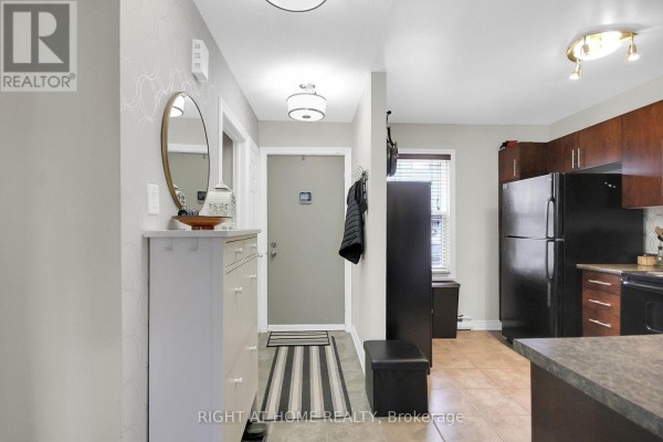 Entrance hallway with a tall shoe cabinet, round mirror, and a doorway to the kitchen. - 16 - 1250 Mcwatters Road N, Ottawa