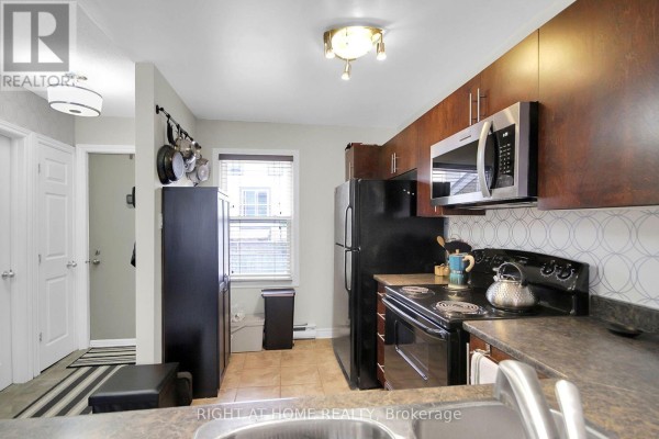 Kitchen with dark wood cabinets, black appliances, a window, and a tiled floor. - 16 - 1250 Mcwatters Road N, Ottawa