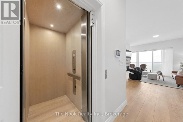 Interior view of a modern elevator with wood paneling and stainless steel details. - 16 - 19 West Street N, Kawartha Lakes