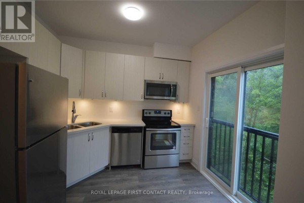 Kitchen with white cabinets, stainless steel appliances, and balcony access. - 16 - 199 Ardagh Road, Barrie