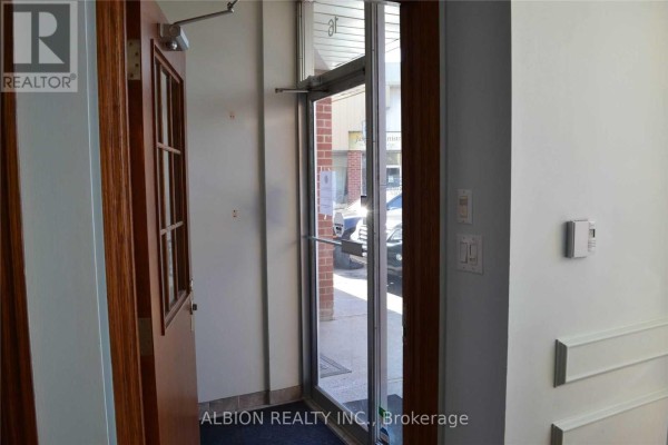 Interior view of commercial building entrance hallway with wooden doors and glass. - 16 - 2001 Albion Road, Toronto