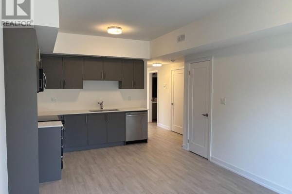 View of a hallway with a white door and an adjacent grey kitchen. - 16 - 42 Lowes Road W, Guelph