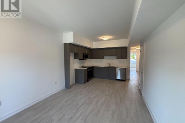 Open concept living area with a modern grey kitchen and light wood flooring. - 16 - 42 Lowes Road W, Guelph