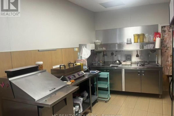 Commercial kitchen area with stainless steel counters, sinks, and food preparation equipment. - 16 - 5418 Yonge Street, Toronto