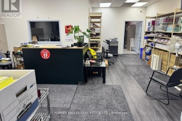 Reception area with dark counter, shelving, boxes, plants, and chairs in an office space. - 16 - 60 West Wilmot Street, Richmond Hill