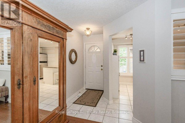 Front entryway with tiled floor, white door, and wooden armoire. - 16 - 784 Gordon Street, Guelph