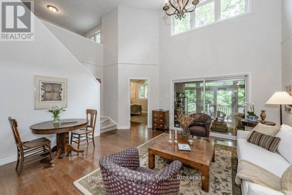 Living room with high ceilings, fireplace, and sliding glass doors to deck. - 16 - 784 Gordon Street, Guelph