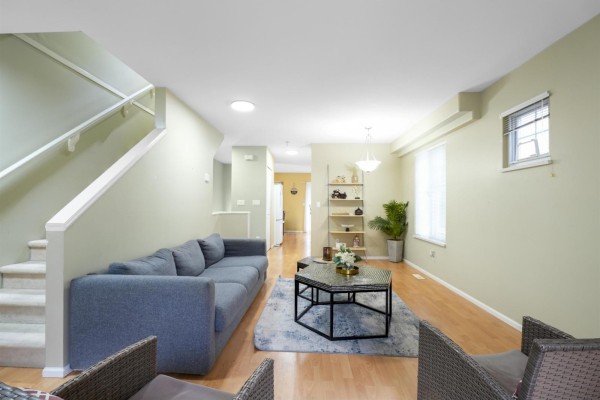 Dining area with a wooden table, chairs, and an open-concept kitchen with white cabinets. - 16 12110 75a Avenue, Surrey