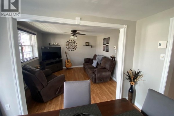 Living room with brown recliners, a sofa, hardwood floors, and a large television. - 16 46th Avenue, Edmundston