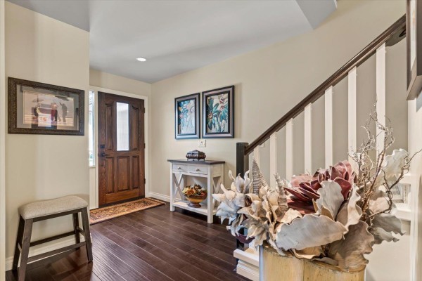 Foyer with a wooden front door, dark wood floors, white staircase, and decorative items. - 16 7001 Eden Drive, Sardis West Vedder, Chilliwack