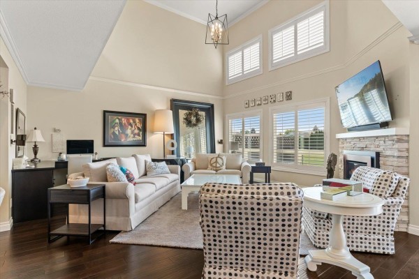 Living room with a high ceiling, fireplace, large windows, and light-colored furniture. - 16 7001 Eden Drive, Sardis West Vedder, Chilliwack