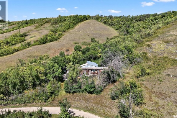 Aerial view of a house nestled in a tree-covered valley with rolling hills behind it. - 16 Alice Crescent, North Grove