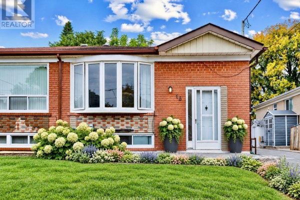 View of the front entrance of a brick bungalow with large potted plants. - 16 Avis Crescent, Toronto
