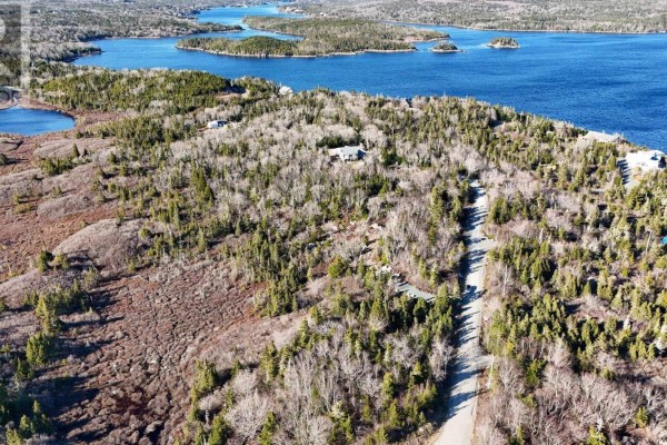 Overhead view of a wooded area with a road winding through it, leading towards a blue ocean inlet. - 16 Bayview Crescent, Prospect