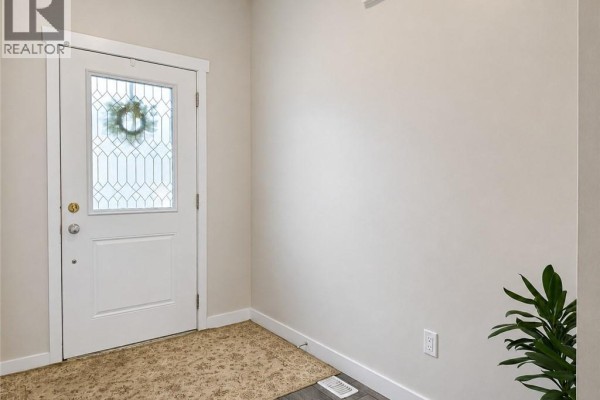 Front porch with decorative door, stone pillars, and potted greenery. - 16 Brookfield Lane, Simcoe