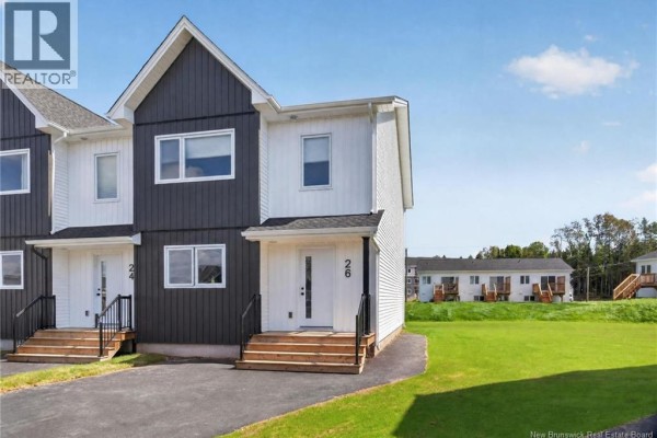 Rear exterior of white vinyl-sided townhouses with small wooden decks and stairs. - 16 Cedric Court, Dieppe