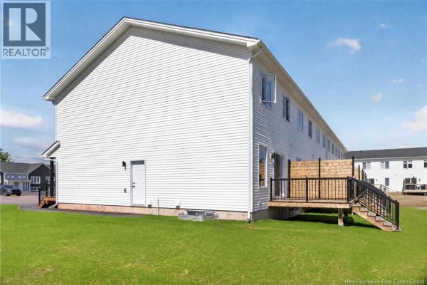 Modern kitchen with white cabinets, stainless steel appliances, black island, and hardwood floors. - 16 Cedric Court, Dieppe
